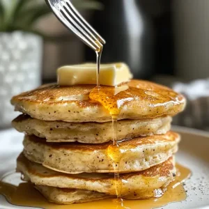 Fluffy pancakes stacked high with butter and maple syrup, with a fork cutting into the stack.