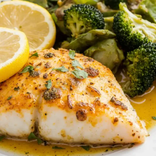 Dijon mustard baked fish fillets served golden and flaky with herbs and lemon on a baking dish