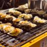 Grilled oysters with garlic butter, herbs, and lemon wedges