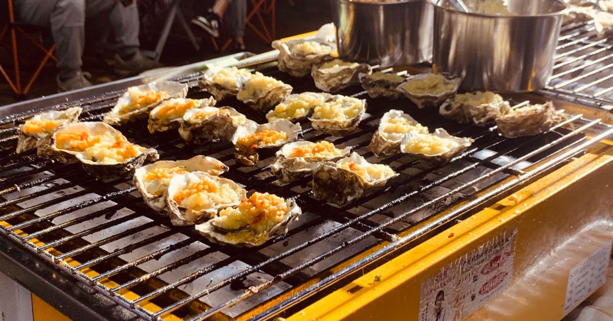 Grilled oysters with garlic butter, herbs, and lemon wedges