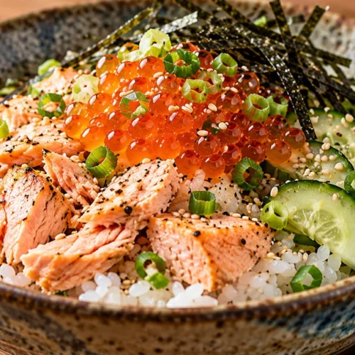 Rice bowl topped with fully cooked salmon, salmon roe, cucumber, scallions and shredded nori