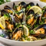 Steamed mussels in opened shells with garlic-lemon broth, parsley and lemon